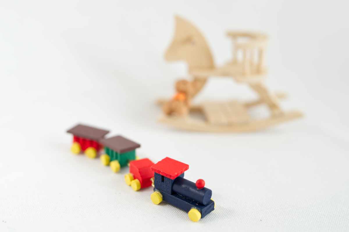 Wichteltür Zubehör Kategorie Spielzeug: bunte Eisenbahn, im Hintergrund Schaukelpferd mit Teddy