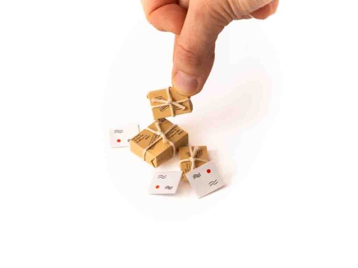 Miniatur Pakete und Postkarten mit Hand im Bild